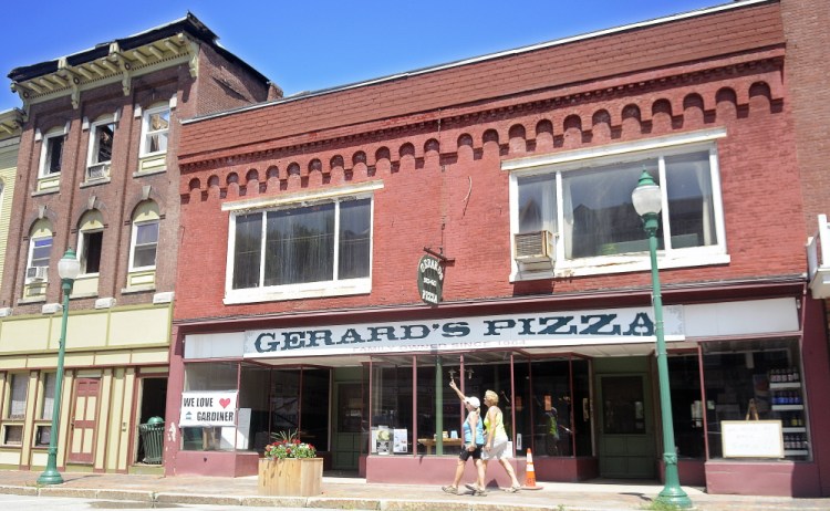 People walk past Gerard’s Pizza in Gardiner, which is next door to the building where the fire started.