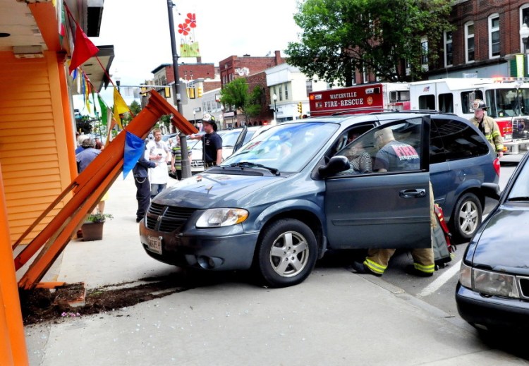 Rescue workers treat Elaine Jacques, the driver of the van that crashed into the front of the Jewel of India Restaurant Thursday morning, smashing a glass entry door and wood structure in front on Main Street in Waterville.