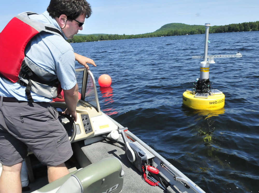 Colby College professor Whitney King approaches a buoy with electronic devices that measure a variety of water quality tests on Great Pond in Belgrade on Thursday.