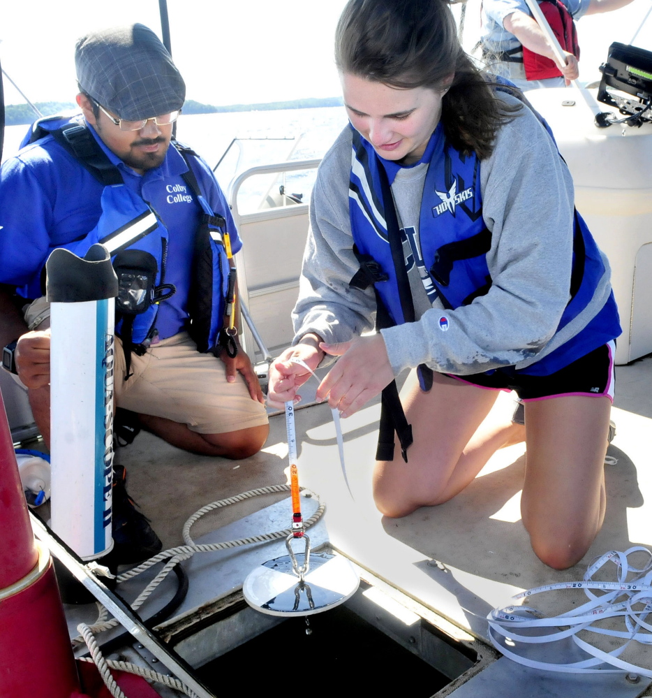 Colby College student Ellie Irish lowers a Secchi disk that measures water clarity as student Sergio Madrigal prepares other equipment to determine water quality on Great Pond in Belgrade on Thursday.