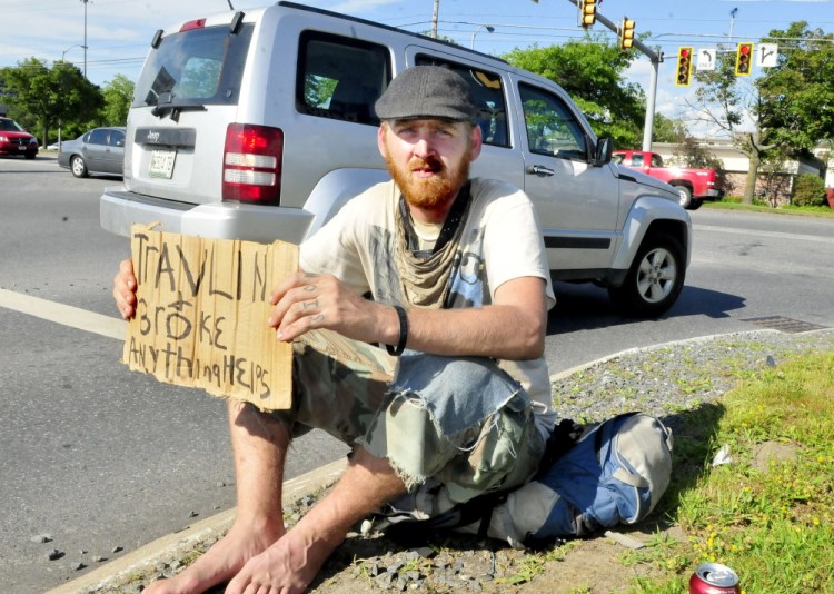 Dewey Wright of Illinois holds a sign asking motorists for help at the end of the Waterville Commons Road in Waterville on Monday.