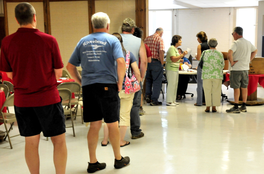 A long line of voters wait for the polls to open at noon Tuesday at the Farmington Community Center to vote on whether to approve the latest Regional School Unit 9 budget.