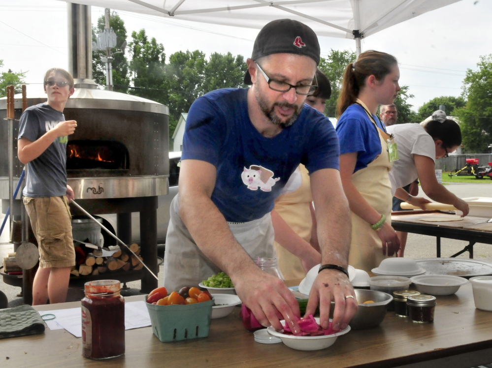 Andrew Janjigian of “Cooks Institute” magazine prepares pizza and bread that was cooked in a wood-fired oven during the ninth annual Kneading Conference in Skowhegan on Thursday.