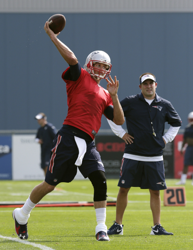 New England Patriots quarterback Tom Brady throws as offensive coordinator Josh McDaniels watches during a training camp practice on Thursday in Foxborough, Mass.
