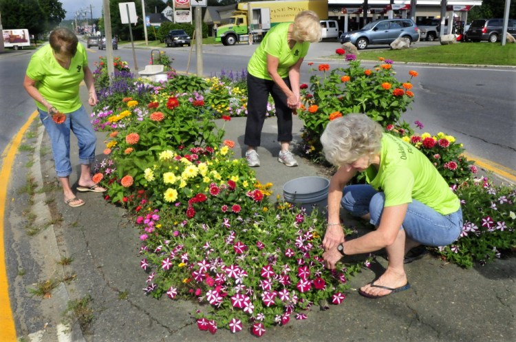 From left, volunteers Terry Borman, Jean Ponitz and Sandy Swartz tend to flowers growing in a traffic island Thursday in downtown Oakland.