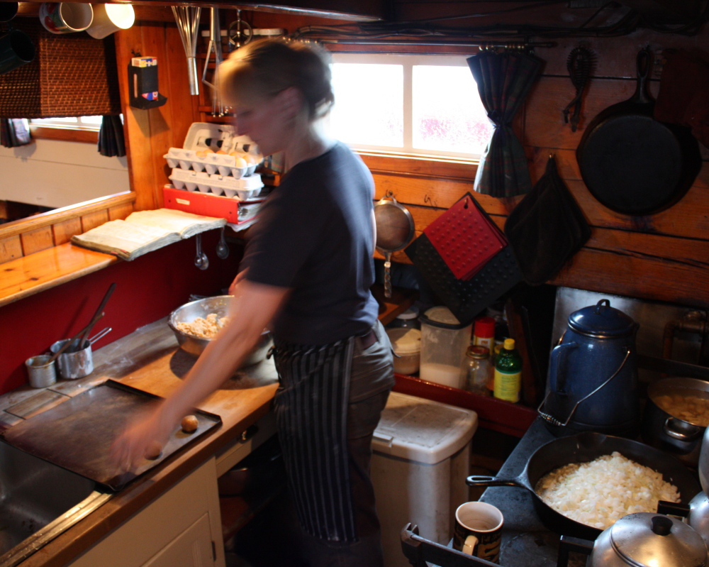 Anne Mahle prepares meals for 30 people at a time in the tiny galley of the Schooner J. & E. Riggin using a wood stove.