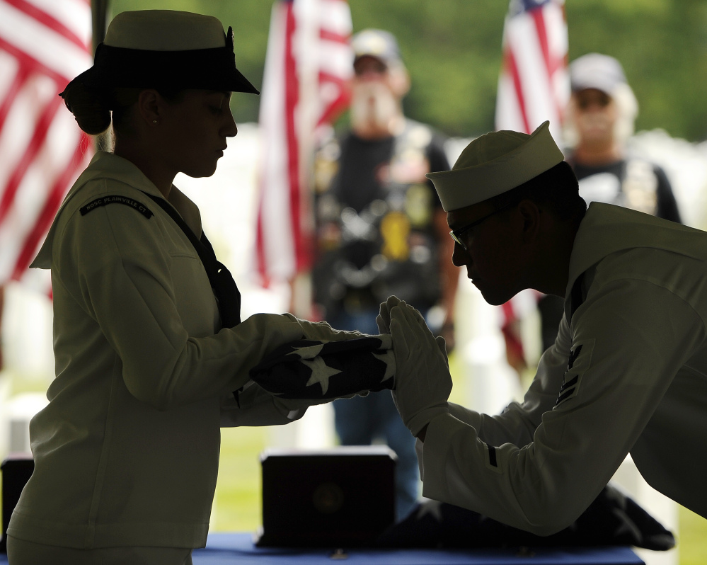 Navy Fireman, Machinist’s Mate Striker Aixa Cruz, left, and Navy Hospital Corpsman 2nd Class James Stringer fold the flag for one of four Connecticut veterans whose unclaimed cremated remains were buried with military honors Wednesday at State Veterans’ Cemetery in Middletown, Conn. The men all died within the past 13 years; no family members could be found.