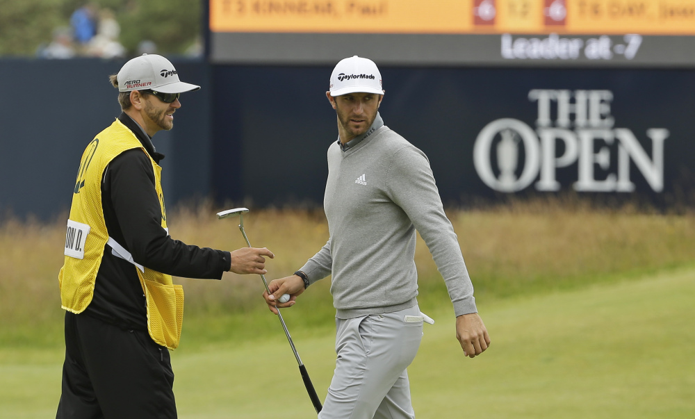 Dustin Johnson hands his putter to his caddie after saving par on the 16th hole during the first round of the British Open. Johnson got through the round without a bogie.