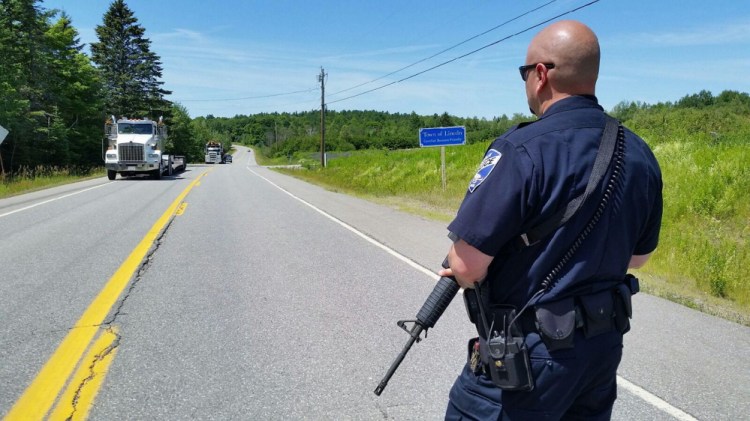 Lincoln Officer Brad Scelso watches as fellow officers turn logging trucks away at the Lincoln-Lee town line on Route 6.