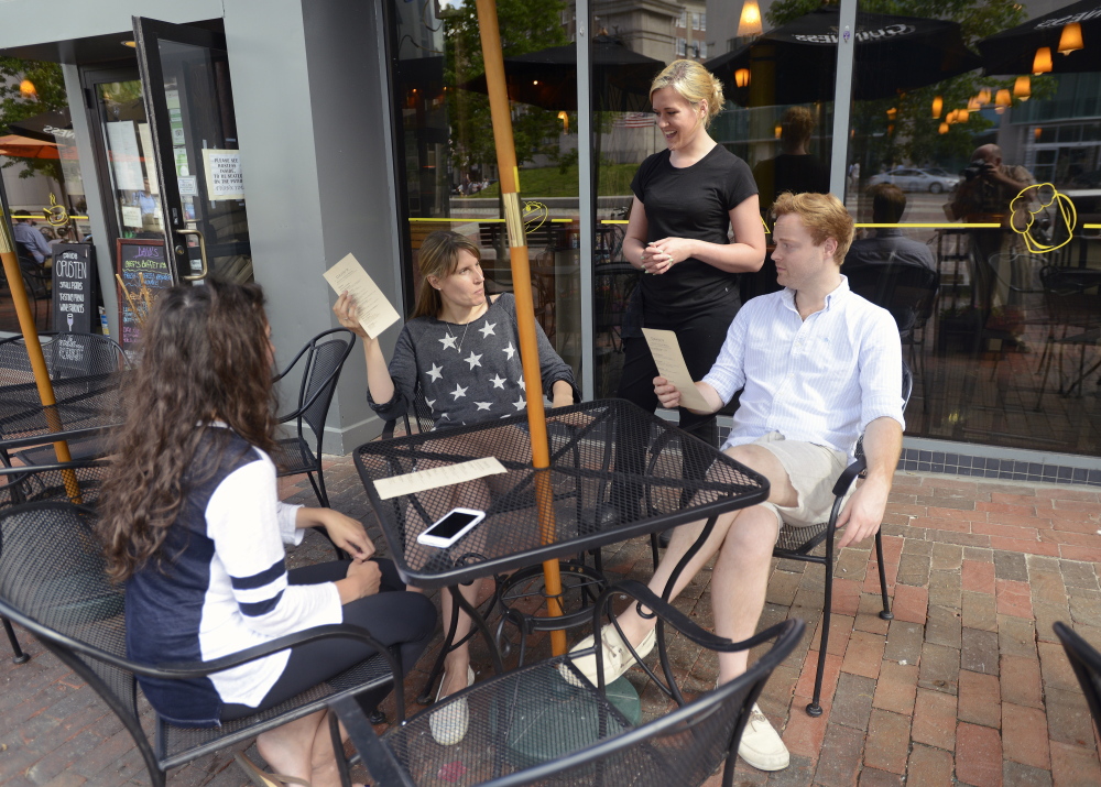 Averil Burner, a server at David’s in Portland, interacts with customers – from left, Brittany Kerrigan-Okamoto and Michelle Kerrigan, both of Palo Alto, Calif., and Matt Paradis of Portland – at the restaurant Thursday. The Maine Department of Labor says about 40 percent of workers earning minimum wage in the city are tipped employees.