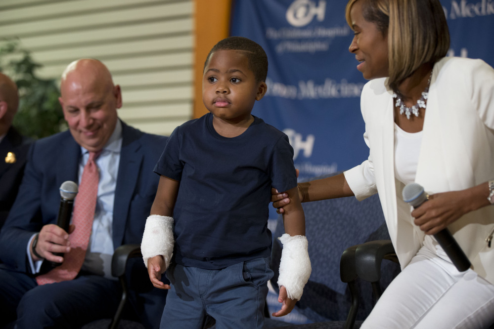 Double-hand transplant recipient Zion Harvey, 8, is accompanied by Dr. L. Scott Levin, left, and his mother, Pattie Ray, at a news conference Tuesday at The Children’s Hospital of Philadelphia. Zion is the youngest patient to receive such a transplant.