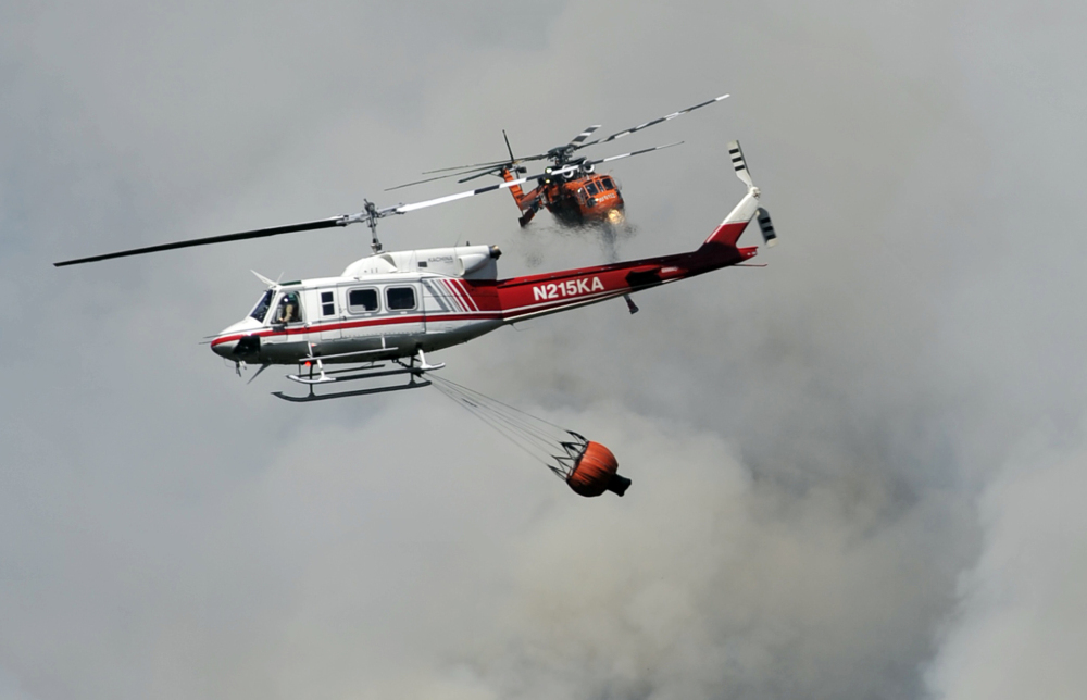 With wildfires raging this summer in drought-stricken California, two firefighting helicopters pass near each other over Willow Creek Canyon near Bass Lake in the central part of the state on Monday.