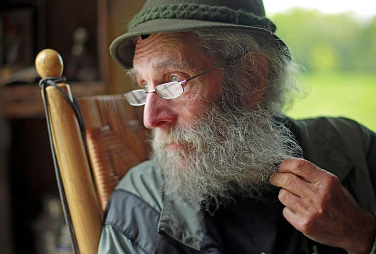 Burt Shavitz pauses during a May 23, 2014,  interview to watch a litter of fox kits play near his camp in Parkman, Maine. Robert F. Bukaty/The Associated Press