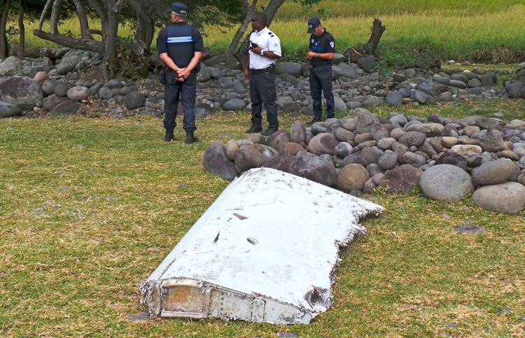 Gendarmes and police stand near a large piece of plane debris that was found on the beach in Saint-Andre, on the French Indian Ocean island of La Reunion, Wednesday. Reuters