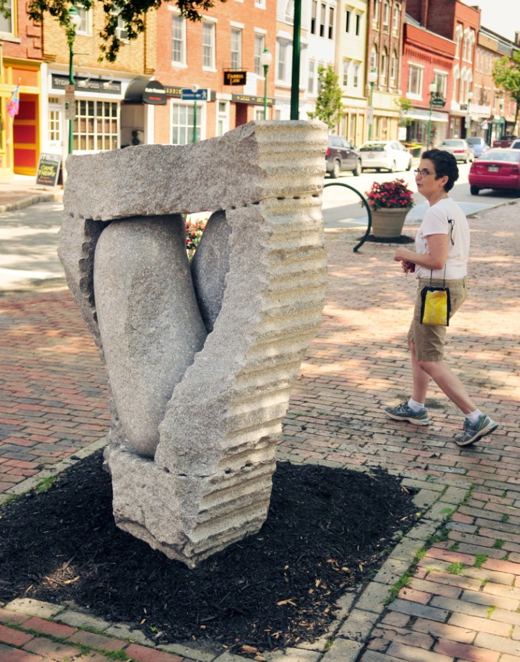 Ellen Roberts looks at a granite sculpture by Maine artist Jesse Salisbury on Thursday in its new, temporary location in downtown Gardiner.