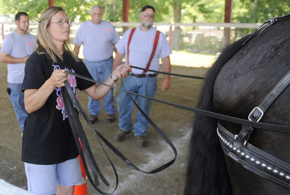 Under the watch of judges, Cathy Simmons, of Sidney, guides a draft horse pulling a log through an obstacle course in the ring at the Monmouth Fair on Sunday.