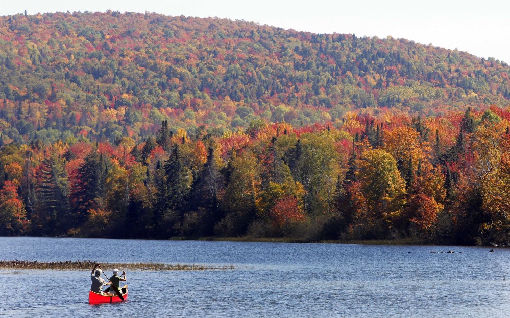 In this Sept. 27, 2014 file photo, Brad and Sue Wyman paddle their 1930’s Old Town Guide canoe along the Androscoggin River as leaves display their fall colors north of the White Mountains in Dummer, N.H. Critics of proposals to import relatively clean hydropower from Quebec into the Northeastern United States worry that transmission lines will despoil New Hampshire’s natural beauty with power lines.