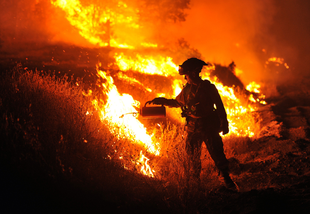 CalFire firefighter Bo Santiago lights a backfire as the Rocky fire burns near Clearlake, Calif., on Monday.