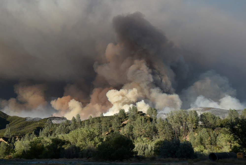 A plume of smoke rises above a hillside as the Rocky Fire burns near Clearlake, Calif., on Monday