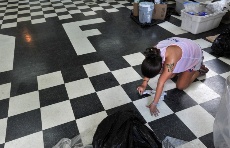 Noel Allan, 16, of Center Valley, Pennsylvania, cleans paint drops from the floor Thursday at the North Anson Fire Station. A group of volunteers put a fresh coat of paint on the station.