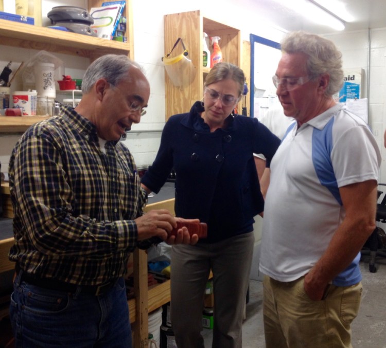 U.S. Rep. Bruce Poliquin, a Republican from Maine’s 2nd District, looks at a product made by Cousineau Wood Products in North Anson with Samantha Warren, his district director. At right is Randy Cousineau, the company’s CEO.