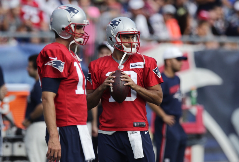 In this Aug. 5 photo New England Patriots quarterback Jimmy Garoppolo, right, clutches the football as he stands with Tom Brady at training camp in Foxborough, Mass.