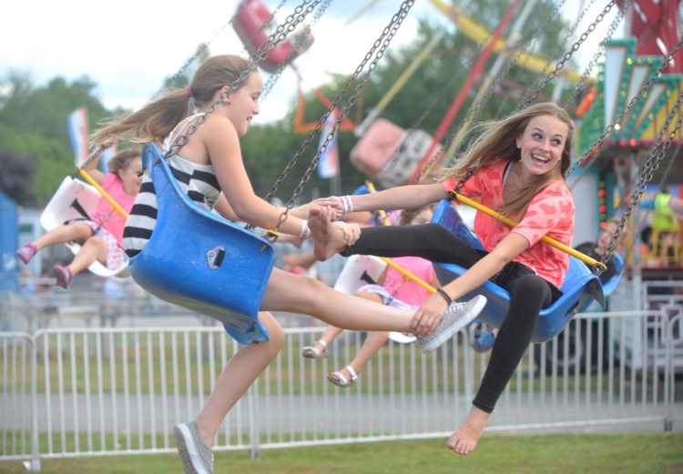 Ellis Sirois, 12, left, and Ashley Corson, 13, right, ride the trapeze swing Thursday on the opening day of the Skowhegan State Fair.