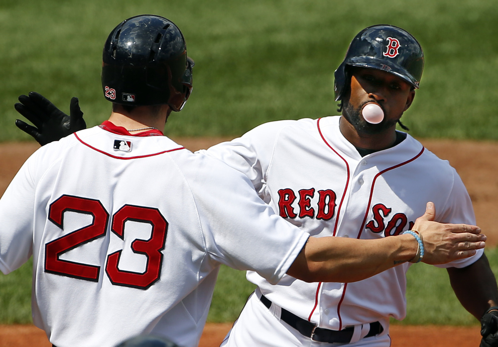 Boston Red Sox’s Jackie Bradley Jr. blows a bubble as he is congratulated by Blake Swihart (23) after his two-run home run against the Seattle Mariners during the second inning Saturday at Fenway Park in Boston.