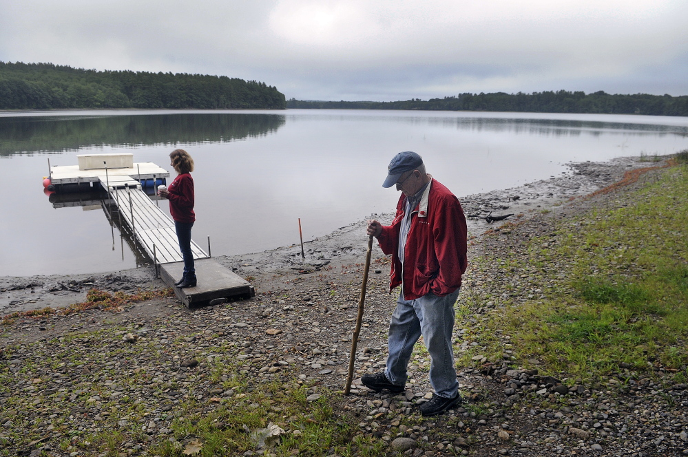 Stan Whittier walks on the shore of Clary Lake in Jefferson Wednesday while his daughter, Jane Roy, stands on the family’s dock. It’s been nearly three years since property owners around Clary Lake in Jefferson and Whitefield appealed to the state to intervene over a low water level, and residents say the situation still hasn’t improved.