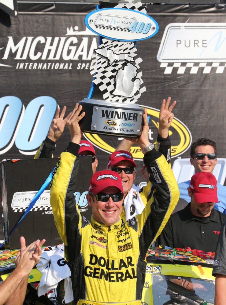 Matt Kenseth raises the trophy after winning the NASCAR Sprint Cup series race at Michigan International Speedway on Sunday in Brooklyn, Mich.