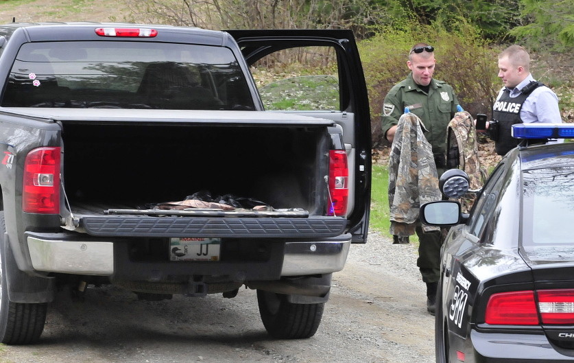 Game warden Dave Ross, left, and Winslow Detective Ron McGowen look over turkey hunting gear, including back packs and two shotguns, from a truck in Winslow on May 5.