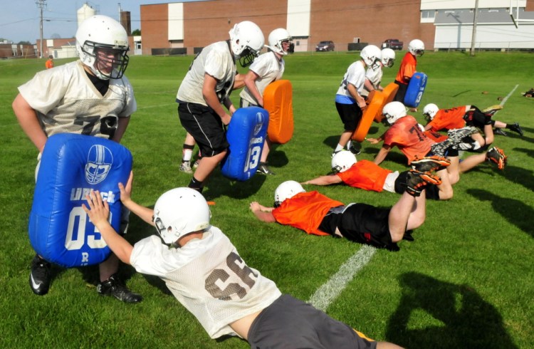 Skowhegan Area High School football players go through defensive drills during practice Monday in Skowhegan.