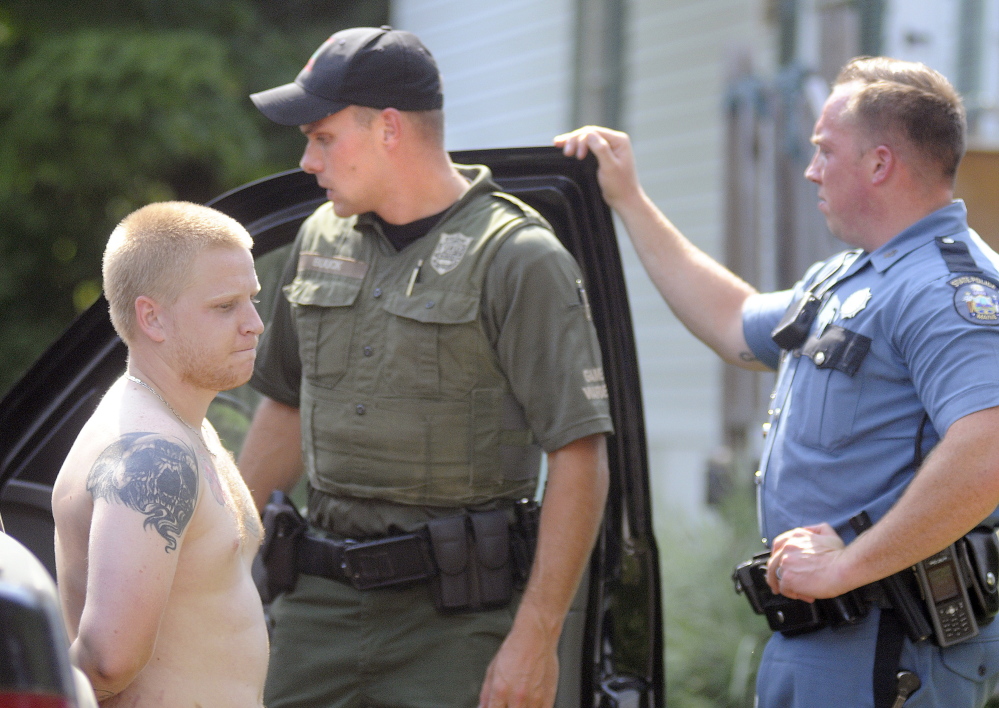 District Game Warden Ethan Buuck, center, and Maine State Trooper Dane Wing arrest Brandon Draveau outside a trailer in Mt. Vernon on Tuesday. Draveau, 22, allegedly fled from Buuck on a dirt bike before being apprehended by the wardens and troopers.