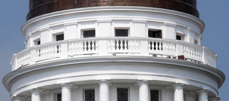 Peeling paint above the pillars around the State House dome in Augusta can be seen Wednesday.