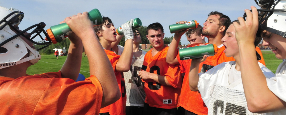 Staff photo by David Leaming 
 Members of the Skowhegan football team cool off during practice Monday. The team took regular breaks as high heat and humidity gripped the region.