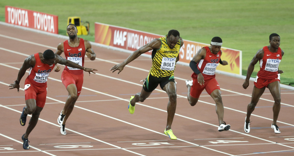 Jamaica’s Usain Bolt, center, crosses the finish line to win the gold medal in the men’s 100m ahead of United States’ Justin Gatlin, left, at the world championships in Beijing on Sunday.