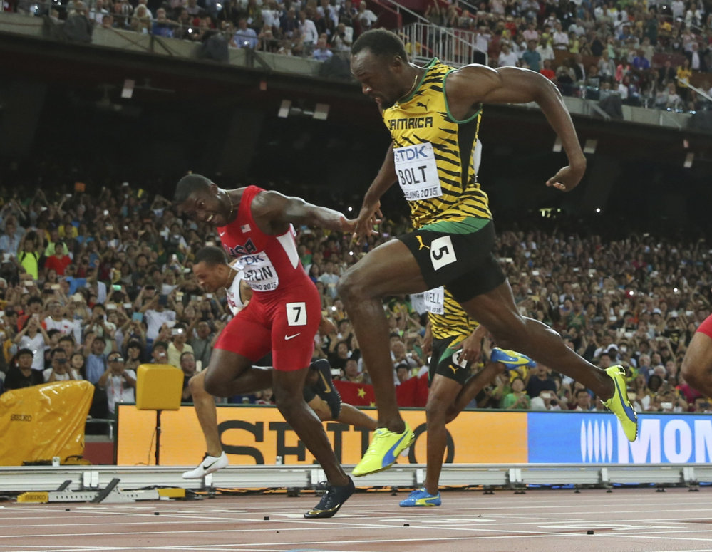 Jamaica’s Usain Bolt crosses the finish line to win the men’s 100-meter final at the world championships at Beijing on Sunday. United States’ Justin Gatlin, left, was second.