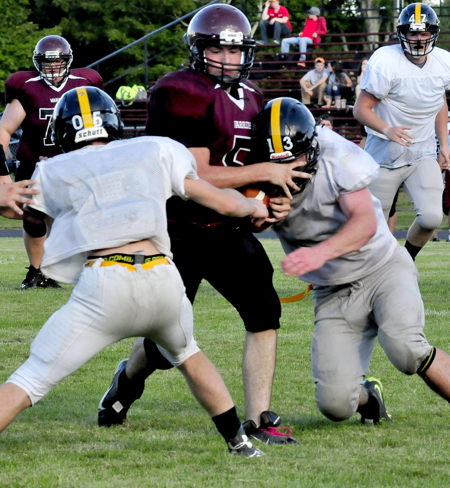 Staff photo by David Leaming 
 Nokomis quarterback Sam Whitmore gets squeezed between two Maranacook defenders during a scrimmage in Newport on Monday.
