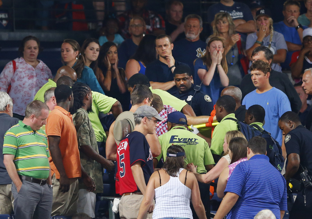 Rescue workers carry an injured fan from the stands at Turner Field during a baseball game between Atlanta Braves and New York Yankees, Saturday in Atlanta.