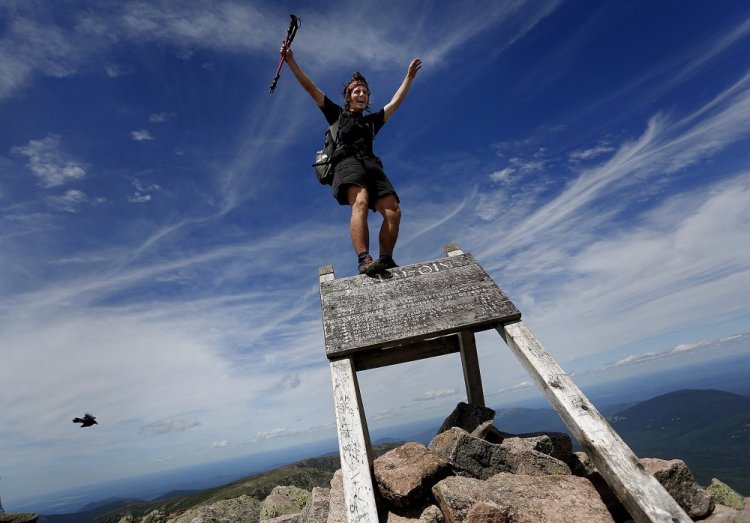 In this July 19 file photo, Jesse Metzler, 19, of Newton, Ma., who goes by the trail name “Sputnik,” celebrates on the top of a sign marking the northern terminus of the Appalachian Trail at the summit of Mt. Katahdin in Baxter State Park. Baxter officials say thru-hikers are openly using drugs and drinking alcohol, camping where they aren’t supposed to and trying to pass their pets off as service dogs. Jensen Bissell, director of the park, says the trail may need to end somewhere besides Katahdin if something doesn’t change soon.