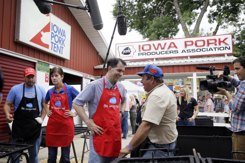 The Associated Press
Republican presidential candidate Wisconsin Gov. Scott Walker talks with Dana Wanken, right, before working the grill at the Iowa Pork Producers tent during a visit to the Iowa State Fair on Monday in Des Moines, Iowa, where he talked about immigration.