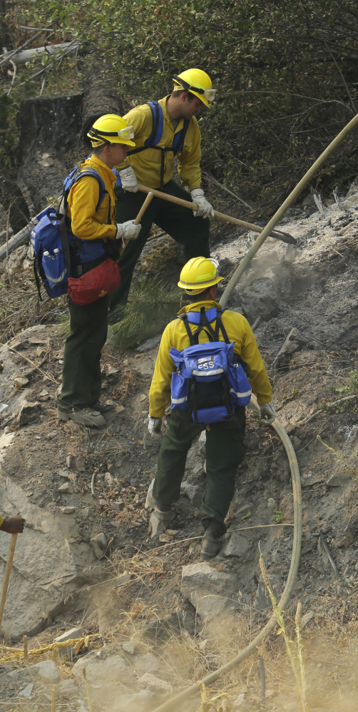 Firefighters and Washington National Guard soldiers work Wednesday to extinguish hot spots near Chelan, Wash.