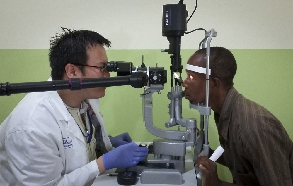 Dr. Zan Yeong, left, an eye specialist for a joint Liberian-American Ebola project, examines the eyes of Ebola survivor Abraham Moses, who has problems with his vision, in Monrovia.