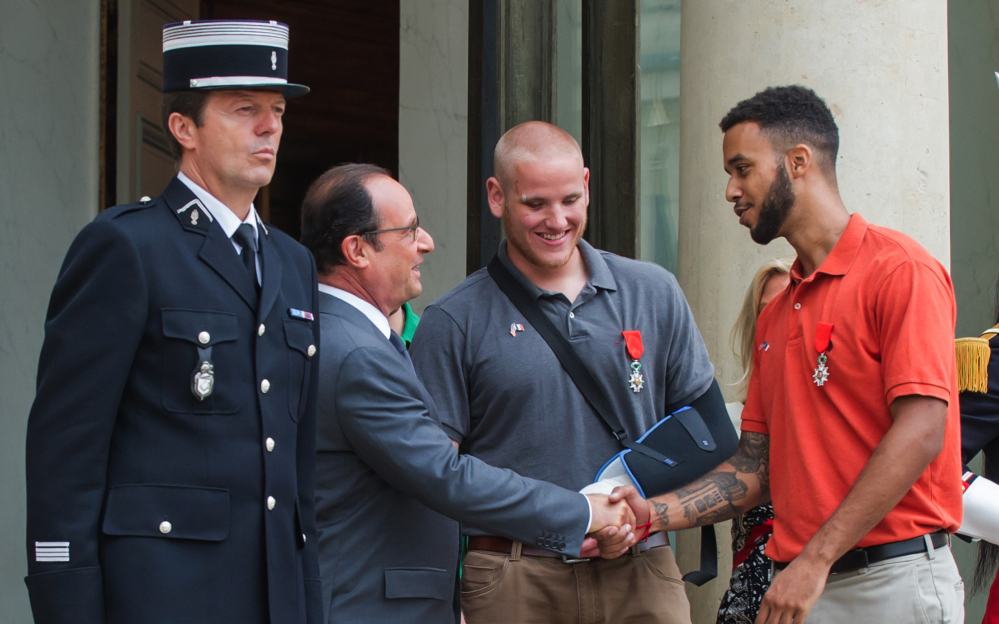 French President Francois Hollande shakes hands with Anthony Sadler, a senior at Sacramento State University in California, while Airman Spencer Stone looks on as they leave the Elysee Palace after Hollande awarded them the Legion of Honor on Monday.