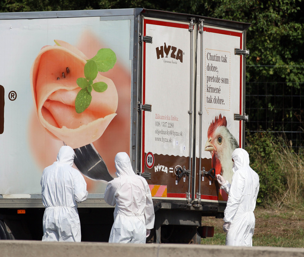 Investigators stand near a  truck that  stands on the shoulder of the highway A4 near Parndorf south of Vienna, Austria, Thursday, Aug 27, 2015. At least 20 migrants were found dead in the truck parked on the Austrian highway leading from the Hungarian border, police said.