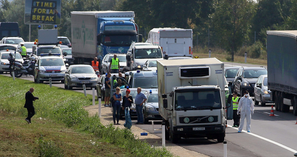 Police stand near a truck that  stands on the shoulder of the highway A4 near Parndorf south of Vienna, Austria, Thursday, Aug 27, 2015. At least 20 migrants were found dead in the truck parked on the Austrian highway leading from the Hungarian border, police said.