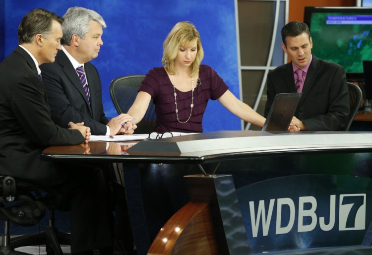 WDBJ-TV7 morning news anchor Kimberly McBroom and meteorologist Leo Hirsbrunner, right, are joined by visiting anchor Steve Grant, second from left, and a Virginia doctor, Thomas Milam, as they observe a moment of silence at the station in Roanoke, Va., Thursday, a day after reporter Alison Parker and cameraman Adam Ward were killed during a live broadcast.