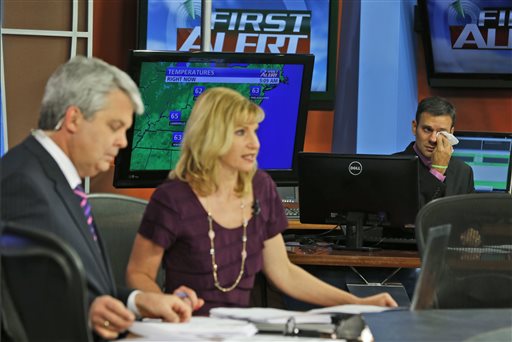 WDBJ-TV7 meteorologist Leo Hirsbrunner, right, wipes his eyes during the early morning newscast Thursday as anchors Kimberly McBroom, center, and guest anchor Steve Grant deliver the news at the station in Roanoke, Va. The Associated Press