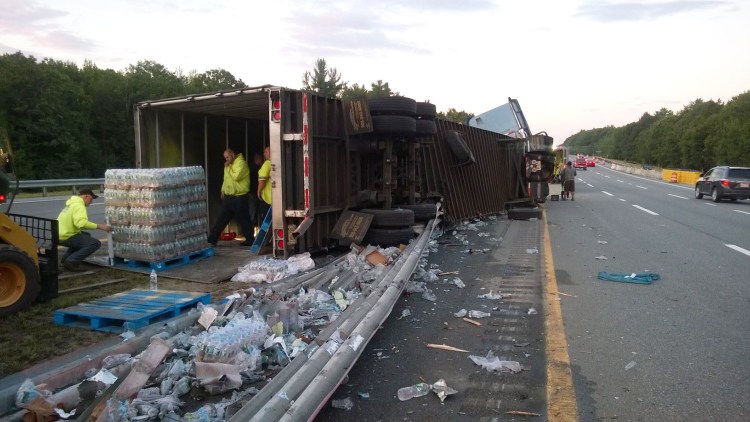 Crews unload a tractor-trailer full of Poland Spring water that overturned on the Maine Turnpike early Monday morning.