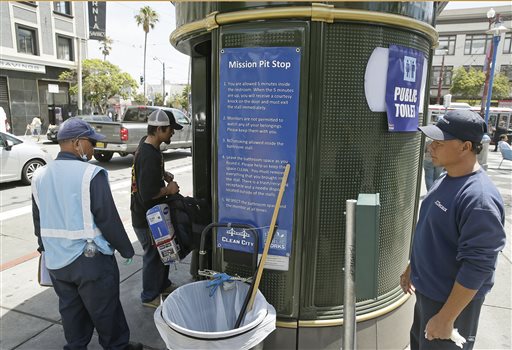 An attendant looks on as a man enters a Pit Stop public toilet outside a Mission District transit station in San Francisco recently. The Pit Stop, located by a public wall covered with a repellant paint that makes pee spray back on the offender, is a project operated by San Francisco Public Works that provides portable toilets and sinks and is part of the city's latest attempt to clean up urine-soaked alleyways and walls. The Associated Press